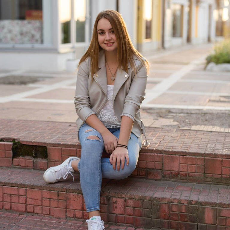 A young beautiful Caucasian female with brown hair sitting and posing at camera
